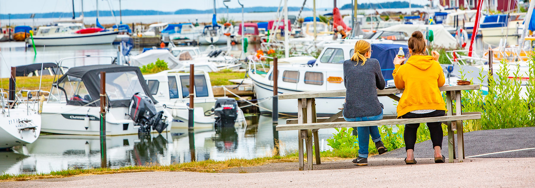 Två kvinnor sittandes på en bänk vid Otterbäckens hamn