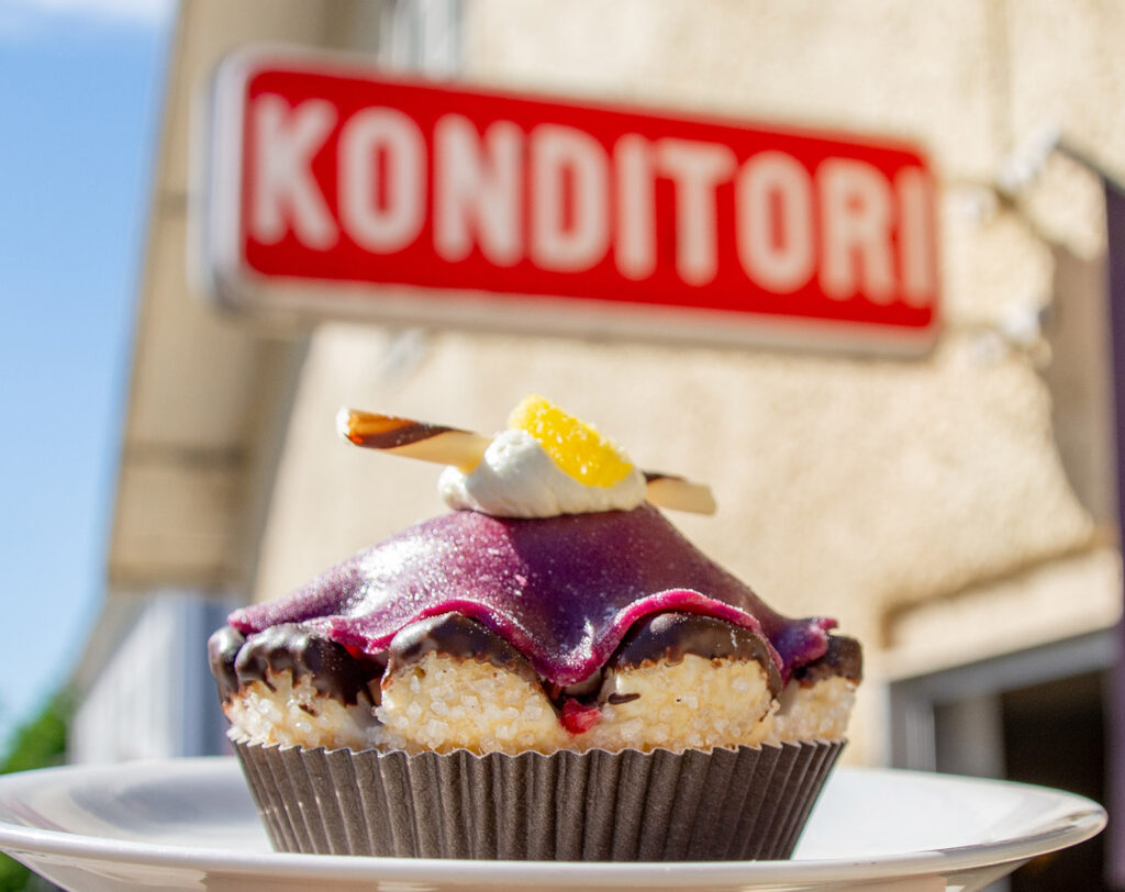 Bild på en bakelse med en konditoriskylt i bakgrunden