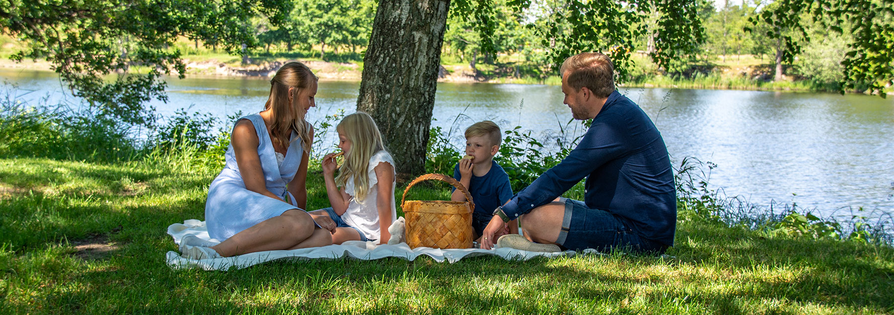 Familj som har picnic vid älven