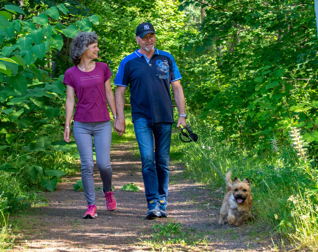 Par med hund som går på en skogsstig