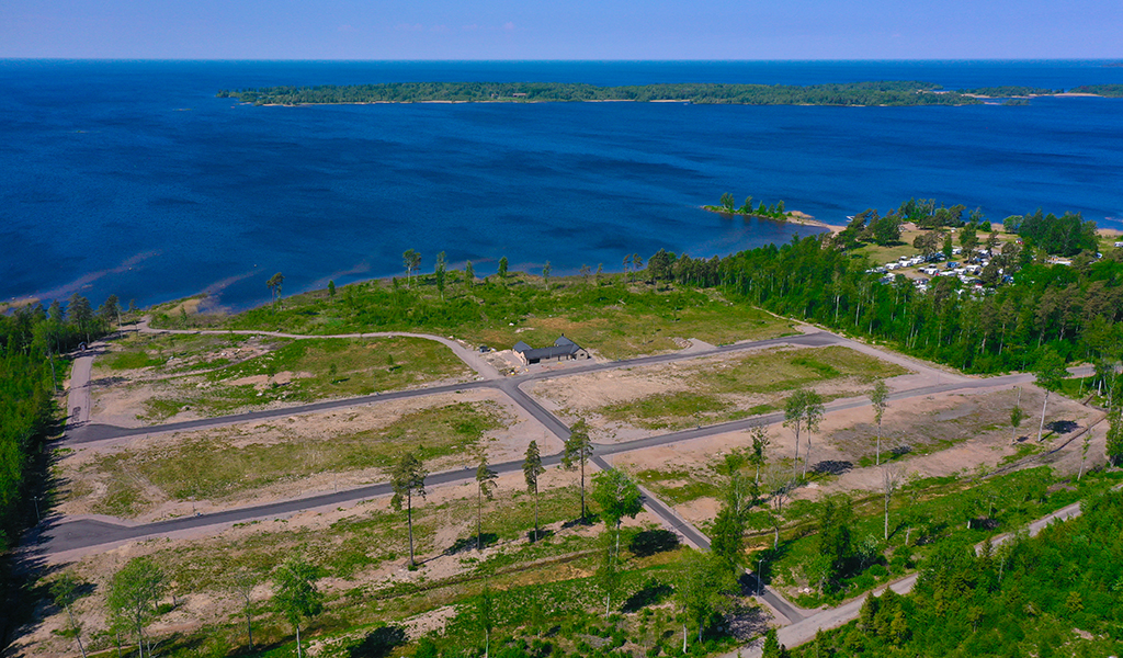 Drönarfoto över ett tomtområde vid vattnet. På bilden finns ett hus.
