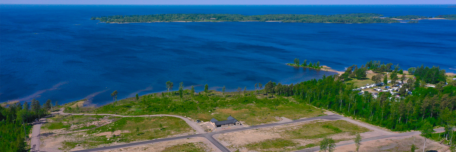 drönarfoto över tomtområde vid vattnet